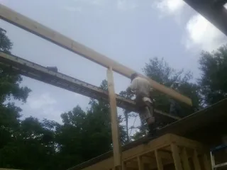 Carpenter setting a ridge beam over a new addition frame — Ice Dam Removal by Roofing Brothers in Johnsonburg