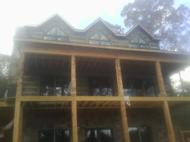 Dormers and porch framing on a large log home under construction — Roof Coating work by our crew in Johnsonburg