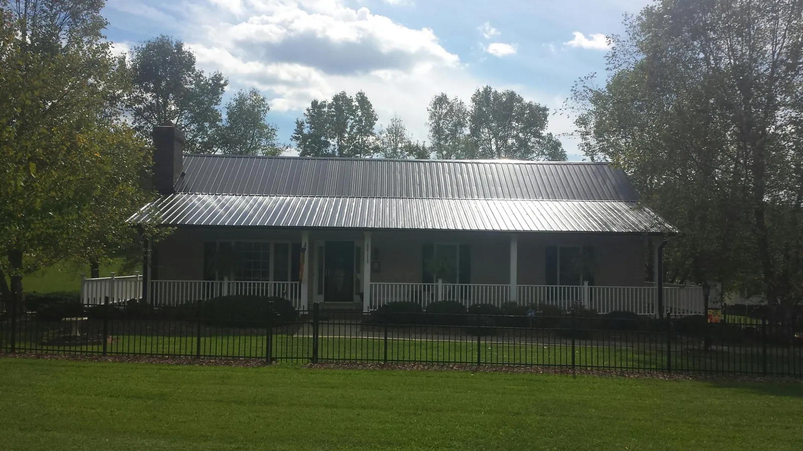 Gray metal roof on a brick ranch with a full width front porch — Gutter Guard Installation work by our crew in Johnsonburg