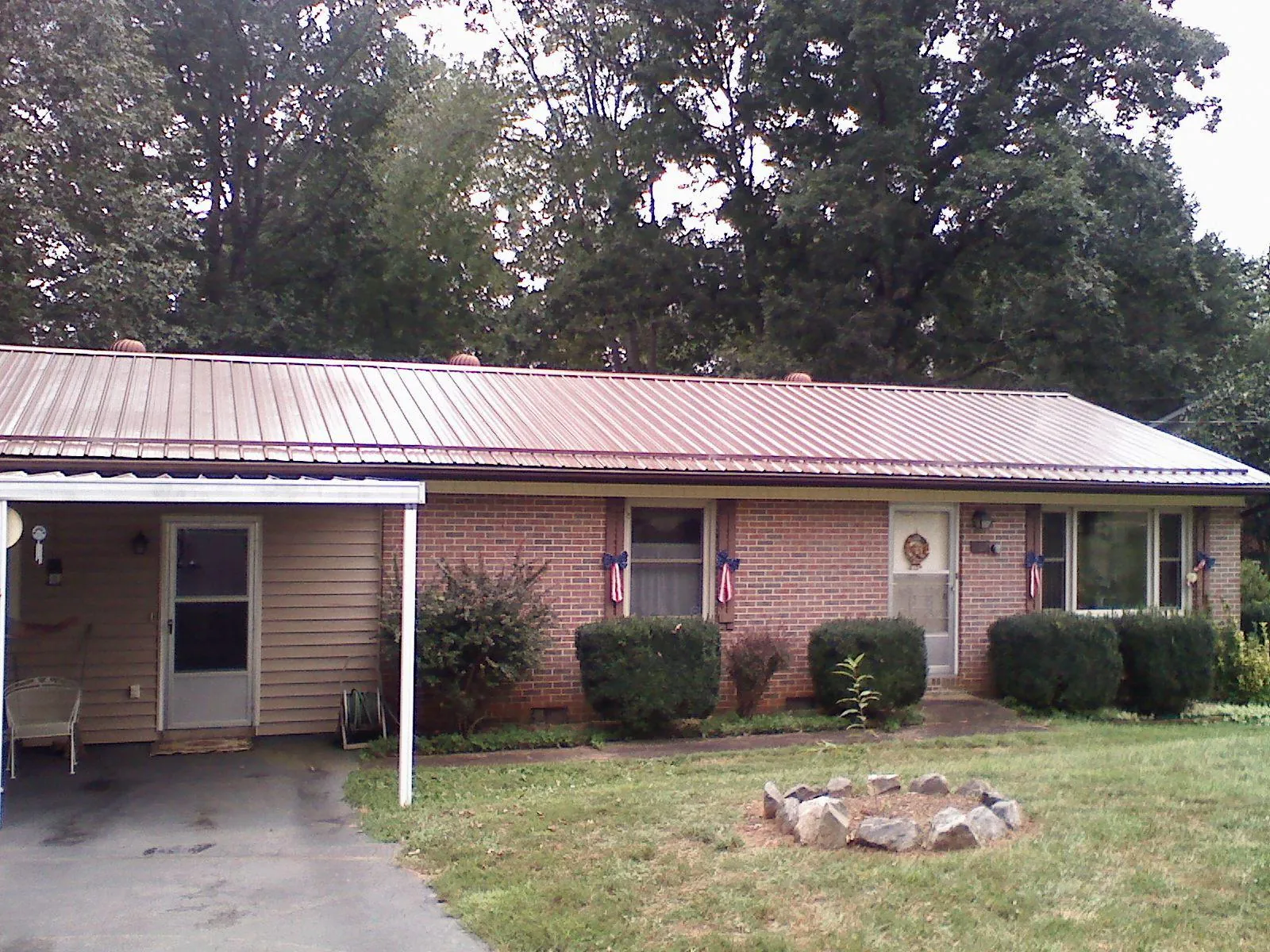 Bronze metal roof and carport on a brick ranch home — Roof Repair work by our crew in Johnsonburg