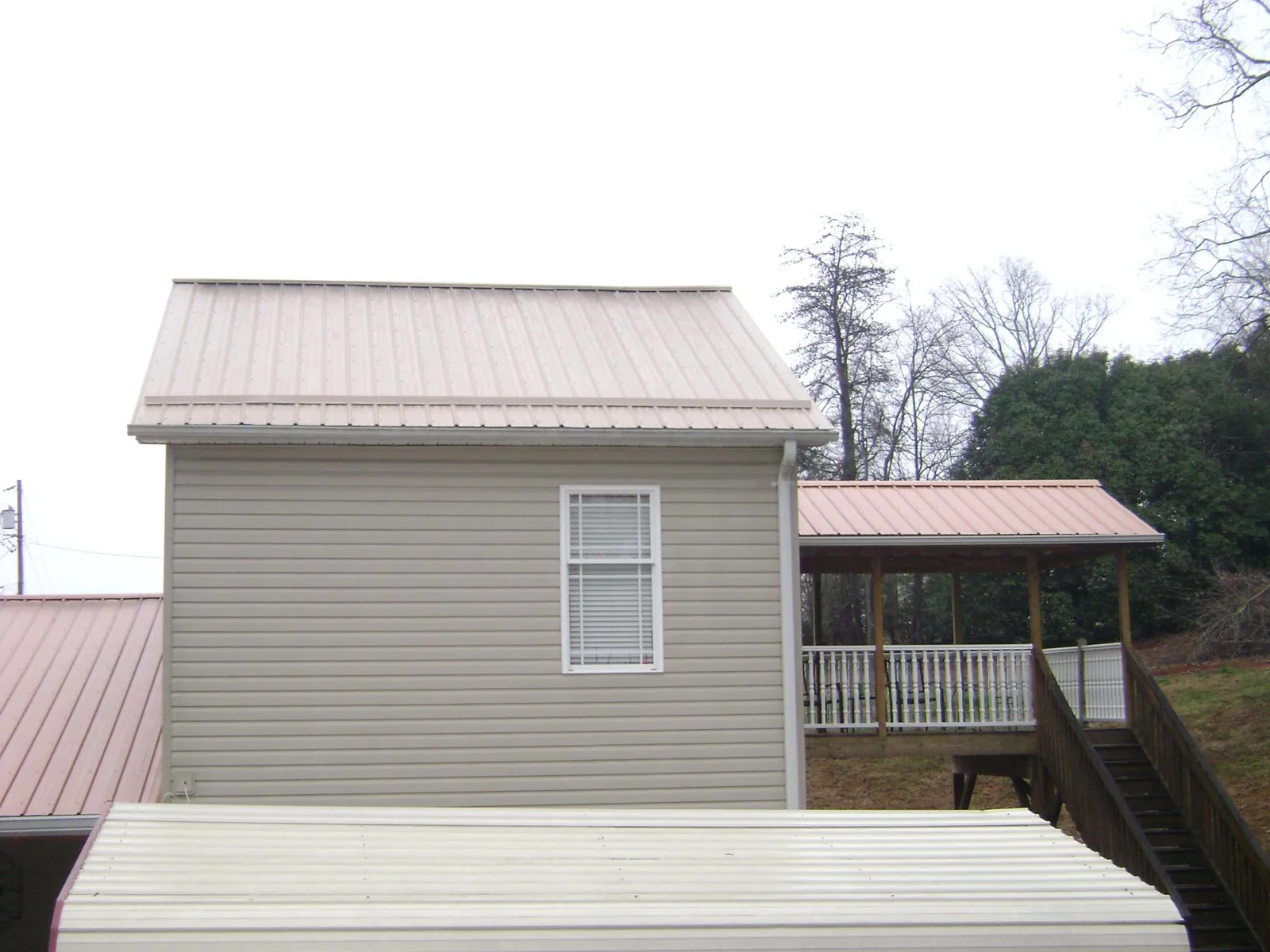 Tan metal roofs on a two story addition and attached porch, from a Roof Replacement job in Johnsonburg