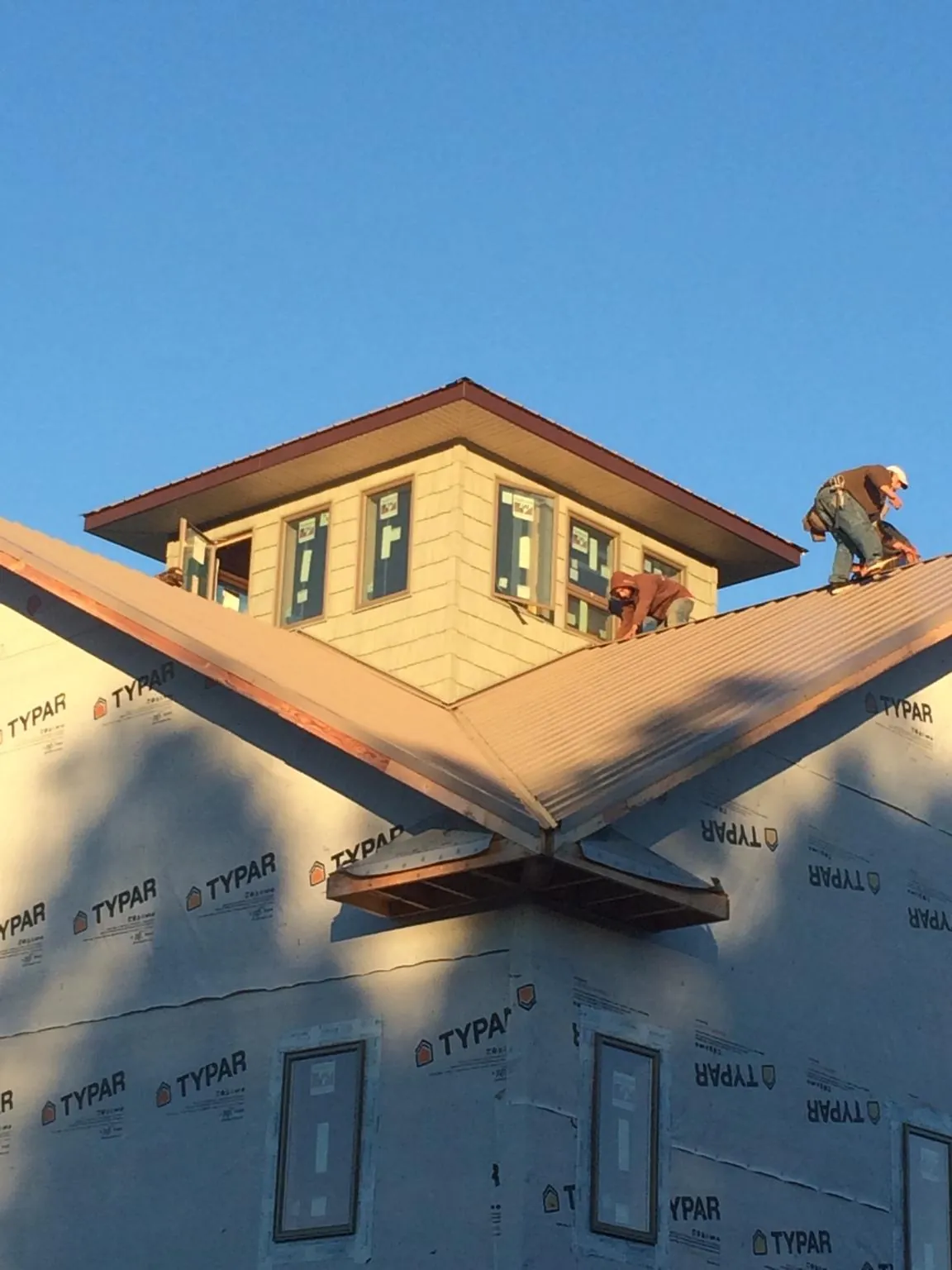 Roofers working around a rooftop cupola on a new metal roof at sunset — Roof Waterproofing in Johnsonburg by Roofing Brothers